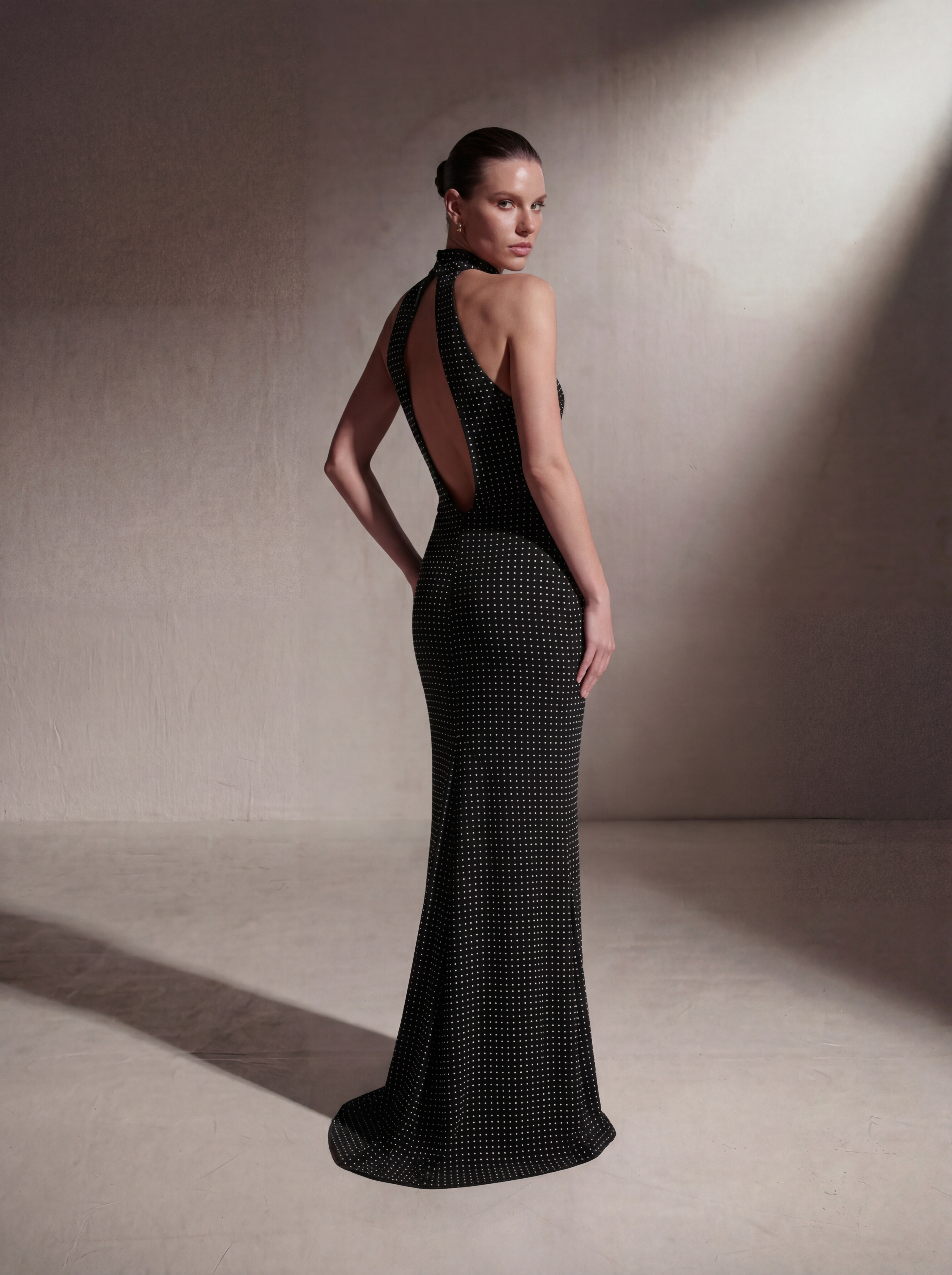 Woman wearing a Black Polka Dot silk halter gown, back view
